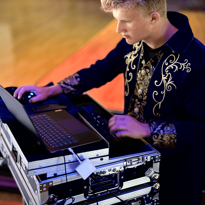 A wedding DJ mixing music from a laptop and controller at a reception
